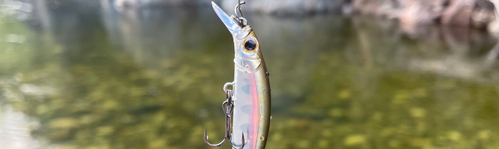 A Jackson Artist FR55 Lure hanging in the foreground with a stream in the background